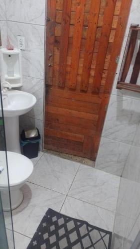 a bathroom with a toilet and a wooden door at Casa da Família in Magé
