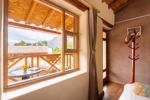 a room with a window with a table and a balcony at Unuwasi Hotel & Villa in Calca