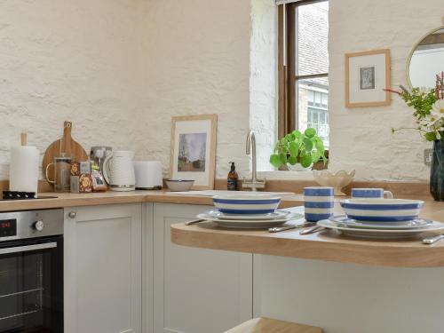 a kitchen with white cabinets and blue bowls on a counter at The Chaff House in Wookey