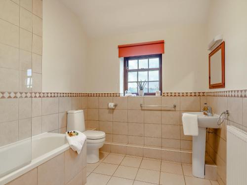 a bathroom with a toilet and a tub and a sink at The Old Combine Shed in Huby