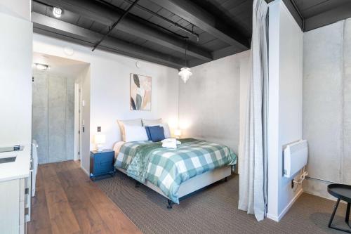 a bedroom with a bed with a plaid blanket at Cozy Studio - Private Balcony Bath and Tub in Lower Hutt