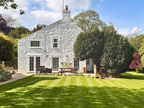 a stone house with a large lawn in front of it at Bathurst Cottage in Scarcliffe