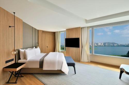 a bedroom with a large bed and a large window at The Westin Mumbai Powai Lake in Mumbai