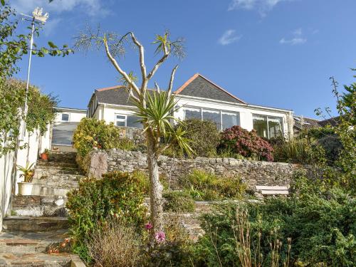 a house with a stone retaining wall and a tree at Sea Cottage in Turnchapel