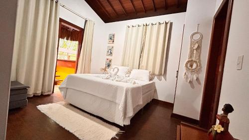 a bedroom with a white bed and a window at Condomínio Valls Village in Itacaré