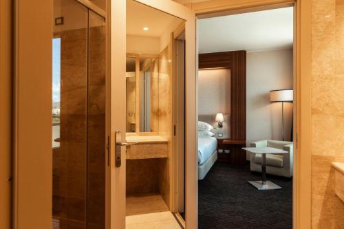 a hotel room with a bathroom and a bedroom at Delta Hotels by Marriott Olbia Sardinia in Olbia