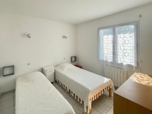 Cette chambre blanche dispose de deux lits et d'une fenêtre. dans l'établissement Maison Plain-Pied avec Jardin Clos à 300m de la Mer - 4 Chambres - WiFi - Bretignolles-sur-Mer - FR-1-231-183, à Bretignolles-sur-Mer