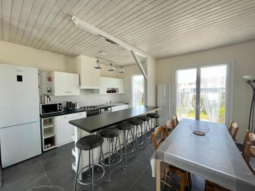 - une cuisine avec une table et des tabourets de bar dans l'établissement **Maison 3 pièces avec jardin à 350m du bord de mer - Wifi, terrasse, parking** - FR-1-231-220, à Bretignolles-sur-Mer