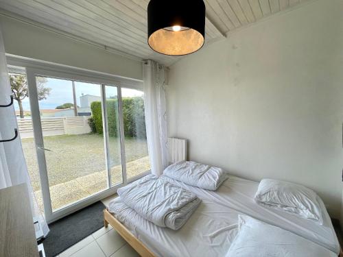 un lit dans une chambre avec une fenêtre dans l'établissement **Maison 3 pièces avec jardin à 350m du bord de mer - Wifi, terrasse, parking** - FR-1-231-220, à Bretignolles-sur-Mer
