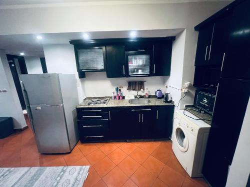 - une cuisine avec des armoires noires et un réfrigérateur blanc dans l'établissement شاليه في بورتو جولف, à El Alamein