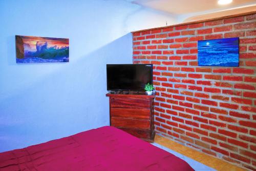 a bedroom with a brick wall and a tv at Queen GrandiaHouse in Puerto Vallarta