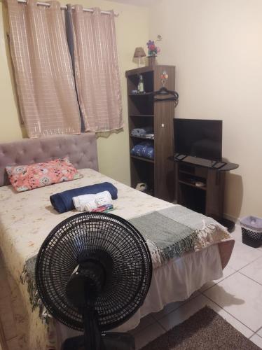 巴西利亚Quarto em casa de Família- Riacho的一间卧室配有一张带风扇和书桌的床。