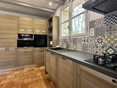une cuisine avec des placards en bois et une grande fenêtre dans l'établissement Villa Charentaise avec Piscine Privée - Jusqu'à 12 Pers. - FR-1-705-89, aux Mathes