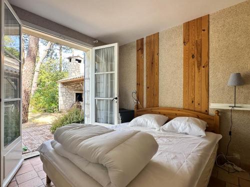 un grand lit dans une chambre avec une grande fenêtre dans l'établissement Villa Charentaise avec Piscine pour 8 personnes à La Palmyre - FR-1-705-103, aux Mathes