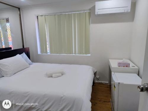 a bedroom with a white bed and a window at Kaban Power 35 in Schofields
