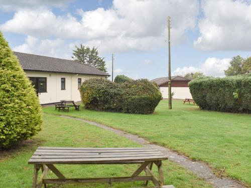 a wooden bench sitting in the grass in a yard at Barn Owls Holiday Bungalow in Salcombe Regis