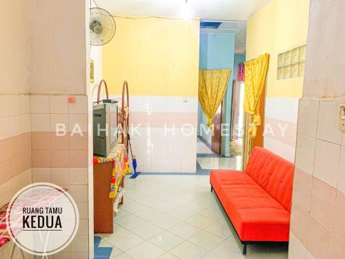 a waiting room with a red couch in a building at Baihaki Homestay in Kota Bharu