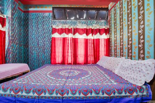 a bed in a room with red and blue at Dekapara Airport Guest House in Kāhārpāra