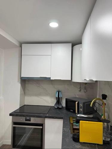 a kitchen with white cabinets and a microwave at Casa do Viriato in Guarda