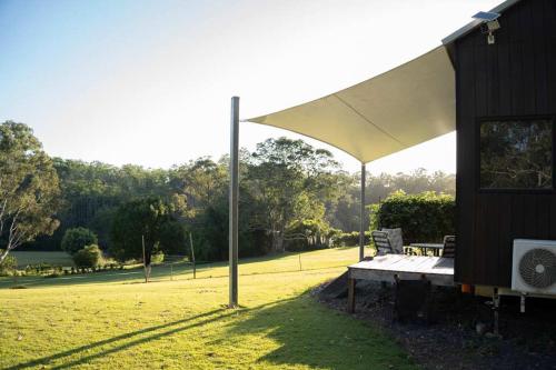 a bench under a white umbrella in a field at Hill Creek Tiny House 1 by Tiny Away in Perwillowen