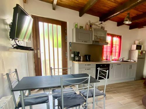 Il comprend une cuisine avec une table et des chaises ainsi qu'une télévision. dans l'établissement Charmante Maison Neuve à Groix - FR-1-813-27, à Groix
