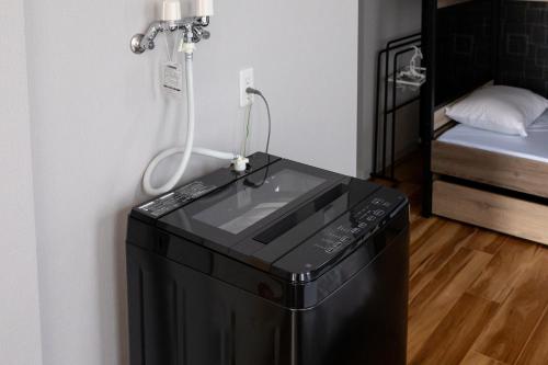 a washing machine in a room next to a bed at Flex cella Tsukisamu in Sapporo