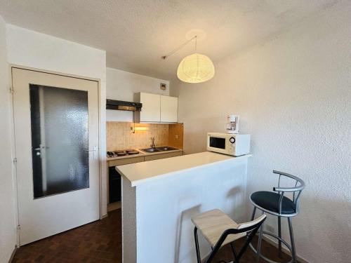 - une petite cuisine avec un comptoir et 2 chaises dans l'établissement Studio cabine avec parking au Cap d'Agde, vue port - FR-1-249-445, au Cap d'Agde