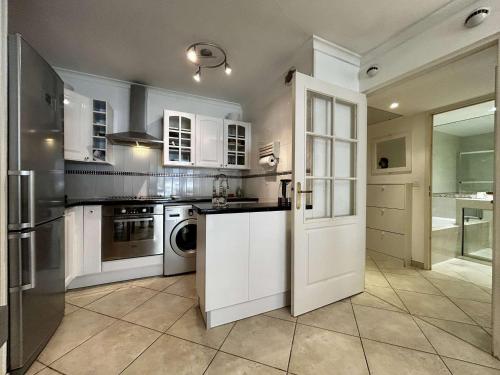 une cuisine avec des armoires blanches et une porte ouverte dans l'établissement Appartement 2 pièces à 5 min de la mer à Golfe-Juan - FR-1-252-200, à Vallauris