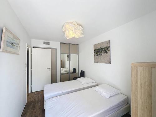 une chambre avec deux lits et un lustre dans l'établissement Appartement 88m2 avec Terrasse et Clim, Piscine Commune à Saint-Cyr-sur-Mer - FR-1-770-56, à Saint-Cyr-sur-Mer
