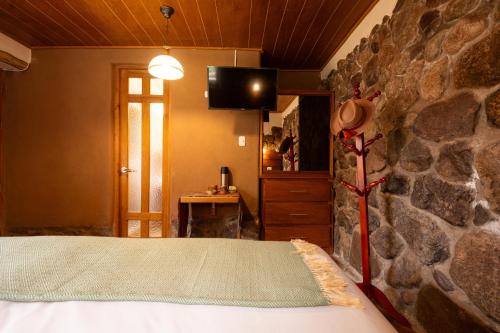 a bedroom with a bed and a stone wall at Unuwasi Hotel & Villa in Calca
