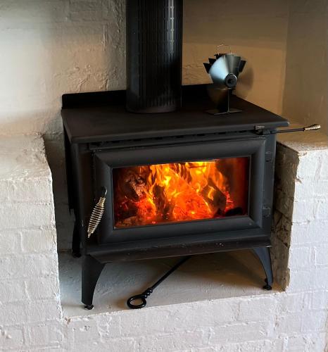 a stove with a fire inside of it at Bylands Cottage Historic Home - Tambo river views and pet friendly in Swan Reach
