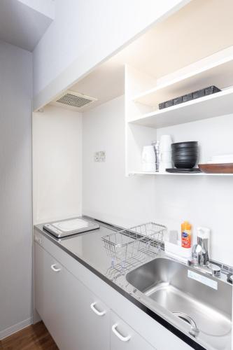 a kitchen with white cabinets and a sink at Flex cella Tsukisamu in Sapporo