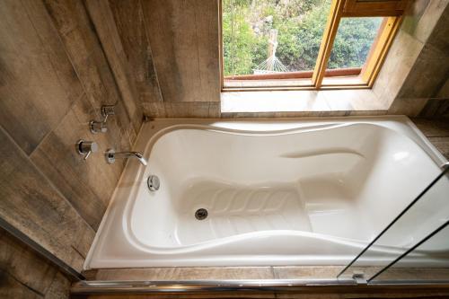 a bath tub in a bathroom with a window at Unuwasi Hotel & Villa in Calca