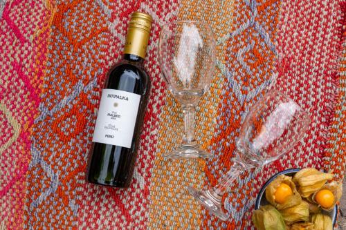 a bottle of wine next to a wine glass at Unuwasi Hotel & Villa in Calca
