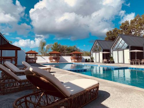 a swimming pool with lounge chairs next to a resort at Yanis Resort in Calatagan
