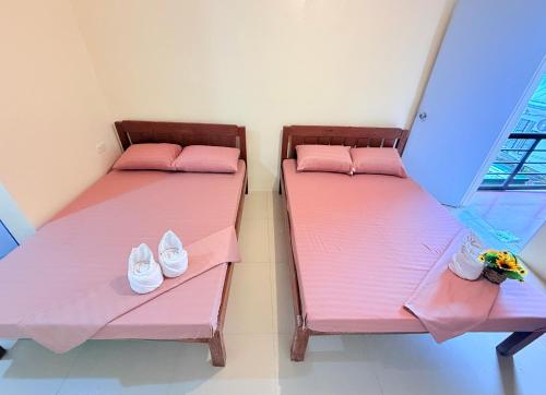 two beds with pink sheets and shoes on them at Ais'G Homestay Tres - 3mins to Airport in Puerto Princesa City