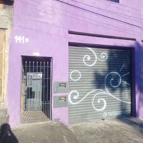 a purple building with a garage door with graffiti on it at Dona Maria - Quartos in Rio Grande da Serra
