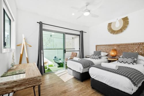 a bedroom with two beds and a sliding glass door at Azur Byron Bay in Byron Bay