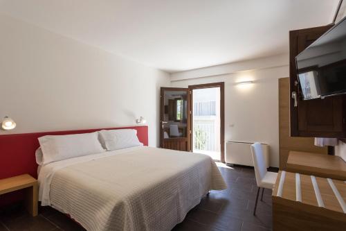 a bedroom with a white bed and a television at Giardino Sul Duomo in Ragusa