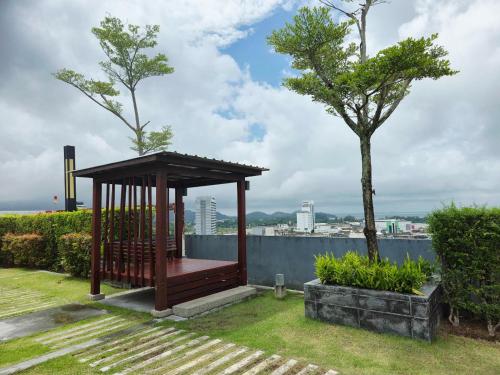 a wooden gazebo on the grass with a tree at Vista Old Town Phuket in Phuket