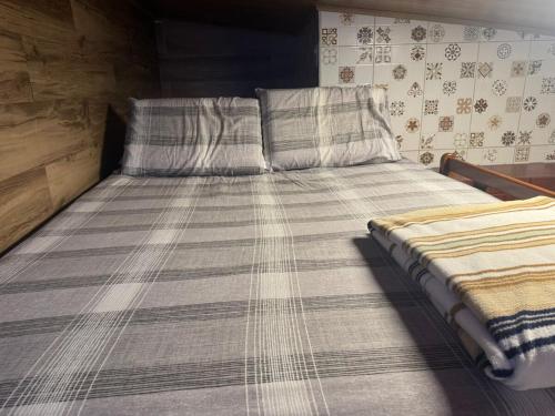 een groot bed met een gestreept dekbed en twee kussens bij 05 Kitnet próximo da praia com ar-condicionado in Maceió