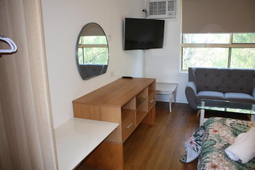 a room with a desk and a couch and a mirror at Coburg Motor Inn in Melbourne
