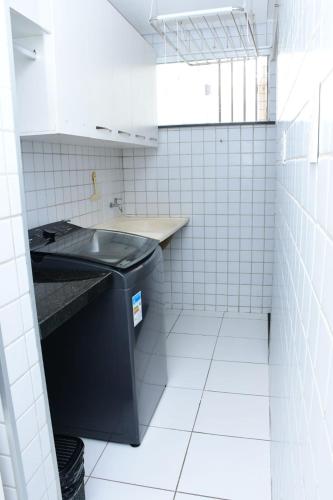 a small white tiled bathroom with a black sink at Apartamento espaçoso e aconchegante in São Luís