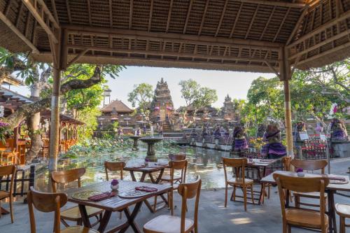 a restaurant with tables and chairs in front of a river at Mumbul Ubud in Ubud