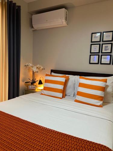 a bedroom with a bed with orange and white pillows at Studio Condo in Saekyung Village One Phase3 in Lapu Lapu City