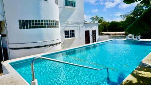 a large blue swimming pool in front of a building at RENOVATED See Belize TRANQUIL Sea View Studio with Balcony, Infinity Pool & Overwater Deck in Belize City