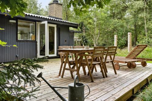 a wooden deck with a table and chairs on it at Forest Vibe And Idyll On Møn in Stege