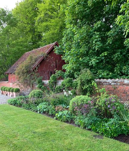a garden with a red barn and a brick wall at Artistic Gardener's House At Kollerup Estate in Hadsten Stationsby