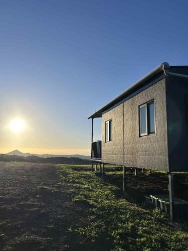 a building in a field with the sun in the sky at Narnoomia Farm Cottage in Belli Park
