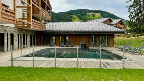 une maison avec une piscine devant dans l'établissement Luxury Penthouse With Mont Blanc Views In Megève, à Megève